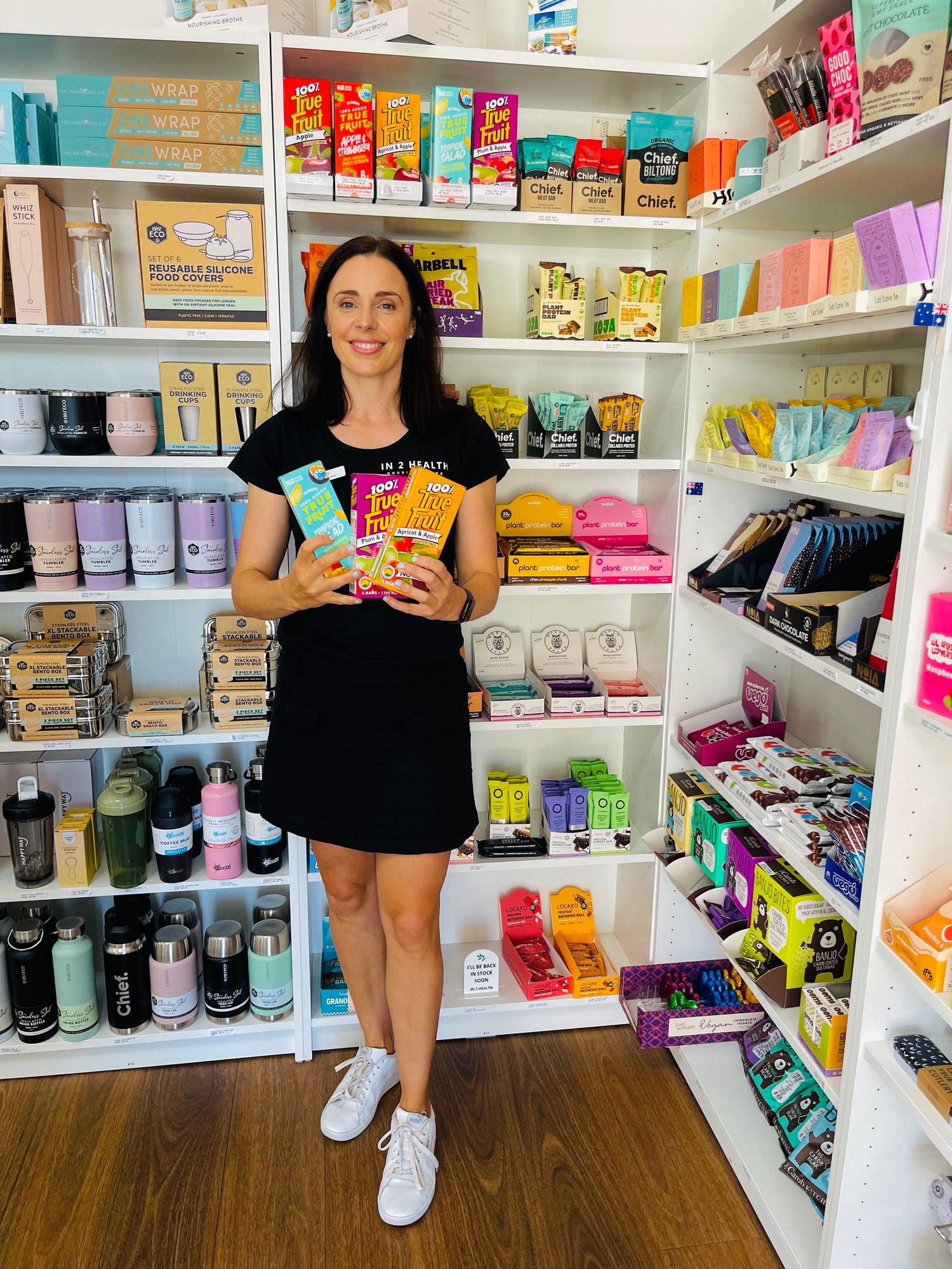 Woman holding healthy snacks and wholefood products at In 2 Health store