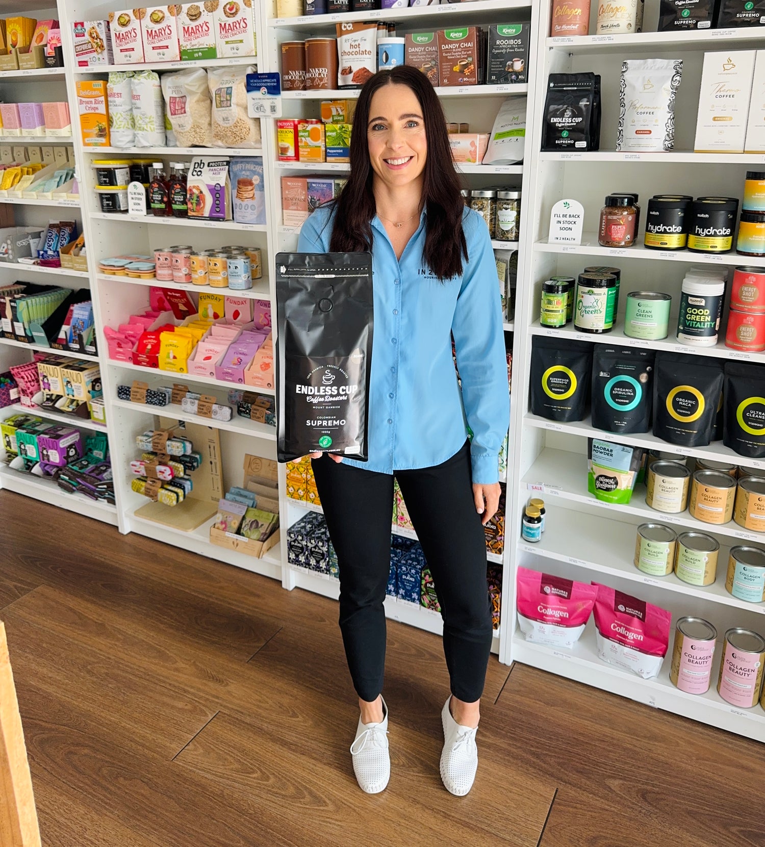 Woman holding a coffee bag in a store with shelves of products